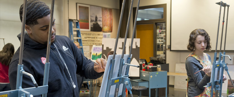 Students painting on easels in art class