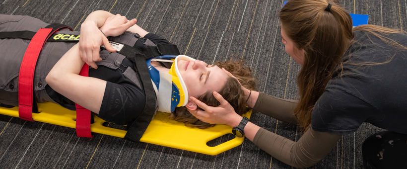 student practices backboarding in emt class